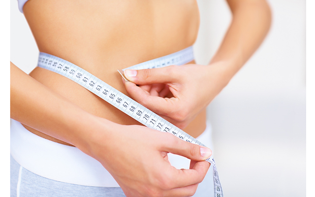 Fit young woman measuring her waistline